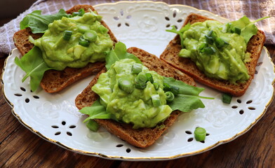 Sandwich with spinach, avocado, green peas and egg on wood background