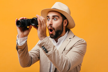 Wall Mural - Man in hat looks surprised into binoculars