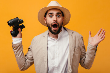 Wall Mural - Guy in hat looks shocked into camera and holding binoculars