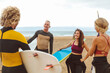 © merla - Group of surfers going to surf in the sea. - Friends enjoying a day of water sport activity.