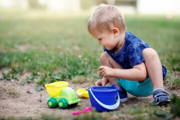 Boy playing with sand and plastic colorful toys