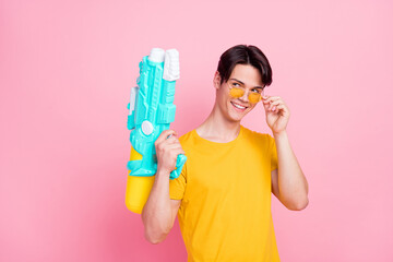 Poster - Photo of young handsome guy happy positive smile hold water gun vacation look empty space isolated over pink color background