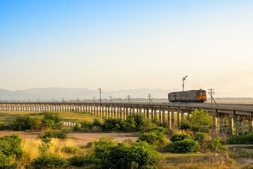 Train runs on a bridge over a reservoir or dam in Lopburi, Thailand.