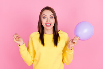 Wall Mural - Photo portrait girl smiling keeping purple air balloon preparing to party in yellow sweater isolated pastel pink color background