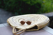 © jelena990 - Round straw bag and retro sunglasses in a garden. Selective focus.