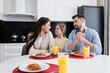 © LIGHTFIELD STUDIOS - happy family looking at each other near croissants and orange juice in kitchen