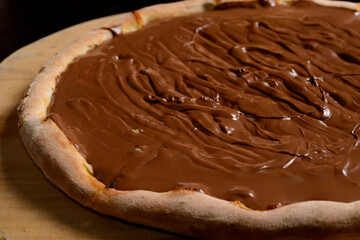 Chocolate pizza on wooden board. Brazilian sweet pizza.