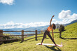 © David Prado/Stocksy - Woman stretching on green yard in mountains