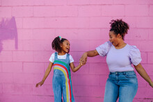Playful Mom And Daughter In Front Of Pink Wall