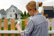 © Danil Nevsky/Stocksy - Young woman applying paint on fence in suburb