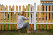 © Danil Nevsky/Stocksy - Woman sitting on haunches and painting fence