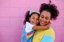 Young Girl Hugging Mom In Front Of Pink Wall