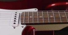 Smooth Sliding On The Neck And Soundboard Of The Electric Guitar. The Guitar Is A Beautiful Red Color. A Fingerboard With Frets And Six Strings. The Overlay Is White And Has Three Pickups. Close-up.