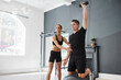 © Nicola Suttle/Stocksy - Personal trainer helping man with dumbbell exercise in gym