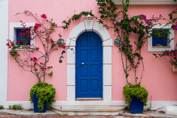 Traditional greek house with colorful blue door and pink walls at Asos village. Assos peninsula famous and extremely popular travel destination in Cephalonia, Greece, Europe.