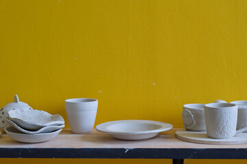 Unfinished clay pots on shelves as part of a ceramic pottery workshop. Creative studio potter. different ceramic dishware on wooden shelves.