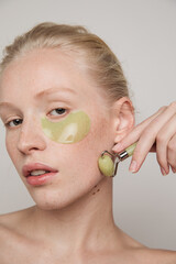 Model with green jade roller and under-eye patch