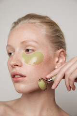 Model with green jade roller and under-eye patch