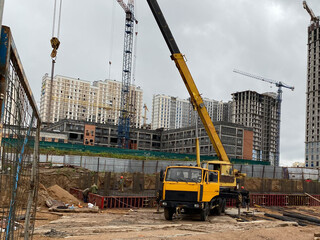 Wall Mural - Image of heavy trucks and building cranes working on the building site at sunny day