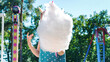 A kid eats a huge amount of cotton candy at an amusement park in summer. Happy carefree childhood concept. Cotton candy in the hands of a child close-up.