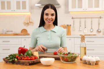 Canvas Print - Happy woman cooking salad at table in kitchen. Keto diet