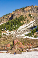 Wall Mural - rocky volcanic mountain landscape with colored rocks, trees, and a blue sky.