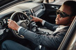 © Fxquadro - Stylish black businessman inside of car holding wheel