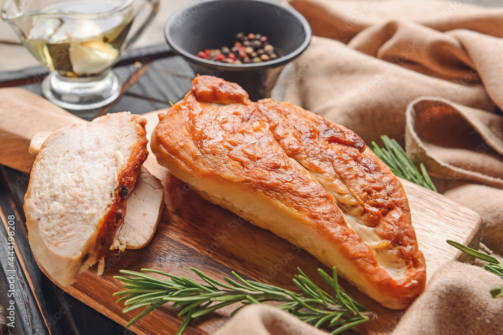 Board with tasty chicken fillet on wooden background