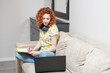 © Павел Костенко - Beautiful caucasian girl is working while sitting on the sofa. Work and education at home