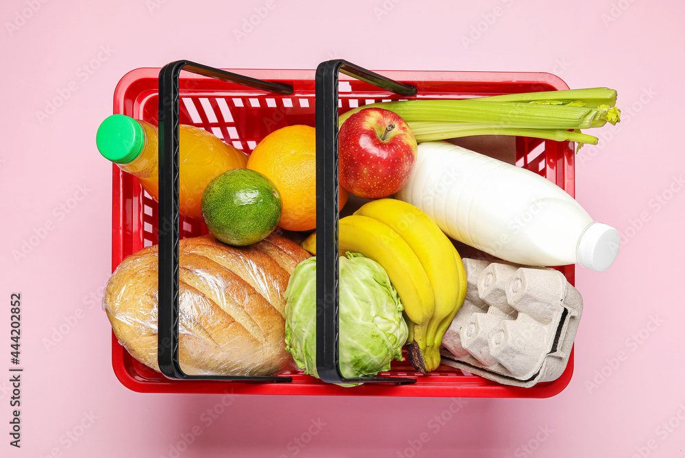 Shopping basket with food on color background