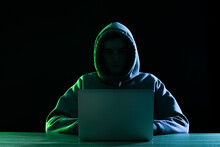 Silhouette Of Hacker With Laptop At Table On Dark Background