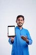 © PRASANNAPIX - Young indian man showing tablet over white background.