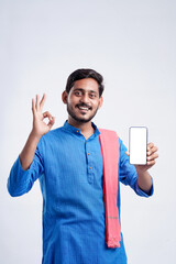 Wall Mural - Young indian farmer showing smartphone and giving expression on white background.