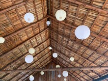 White Paper Lanterns Hanging From The Underside Of A Thatched Roof