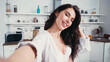 © LIGHTFIELD STUDIOS - sexy woman in white shirt smiling while taking selfie on blurred foreground
