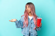 © luismolinero - Young mixed race woman drinking a fresh drink isolated on blue background with surprise expression while looking side