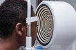 © ADDICTIVE STOCK - Black woman in optometry cabinet using a modern corneal topographer