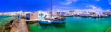Greece Travel. Cyclades, Paros Island. Charming Fishing Village Naousa. View Of Old Port With  Boats And Street Taverns By The Sea.