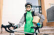 © ADDICTIVE STOCK - Portrait of female courier standing next to bike with parcels