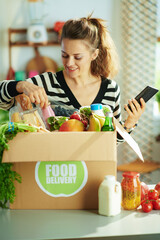 Wall Mural - happy modern housewife with food box in kitchen