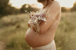 © ADDICTIVE STOCK - Anonymous topless serene pregnant woman covering breast with flowers in field
