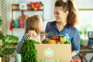 Wall Mural - happy young mother and child with food box in kitchen