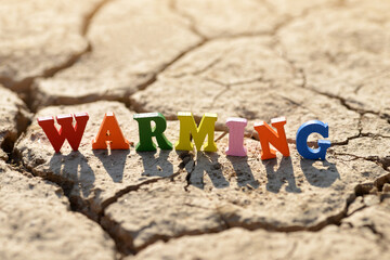 Wall Mural - Text Warming on arid cracked soil. Concept of climate change.