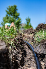 Focus on a black 1 inch sprinkler plastic water line laid in a shallow trench