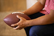 © SuperStock - Detail of man holding football while watching game at home