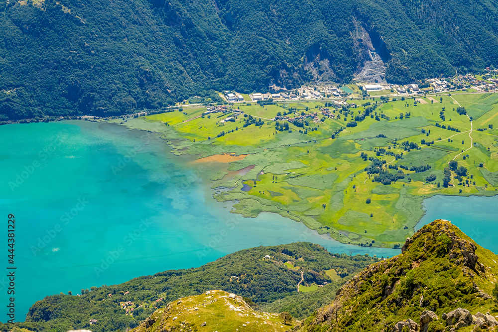 Türkisfarbenes Wasser und grüne Uferlandschaft am Comer See