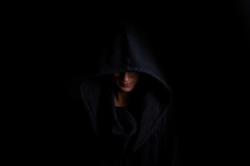 Young woman in a black hood on a dark black background