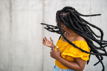 Beautiful young woman dancing in front of gray wall 
