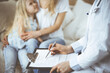 © rogerphoto - Doctor and patient. Pediatrician using clipboard while examining little girl with her mother at home. Sick and unhappy child at medical exam. Medicine concept