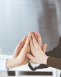 © Iryna - Business people group showing teamwork and joining hands or giving five in modern office. Unknown businessman and women making circle with their hands